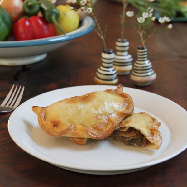 Two golden-brown JAVI'S COOKING Empanadas Argentinas on a white plate, one cut open to show filling.